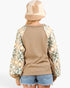 A person shown from the back wearing a tan knit sweater with patterned raglan sleeves, a fuzzy beige and cream beanie, and denim shorts against a plain light background.