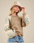 Woman wearing a brown sweater with patterned sleeves and a beige bucket hat on a beige background