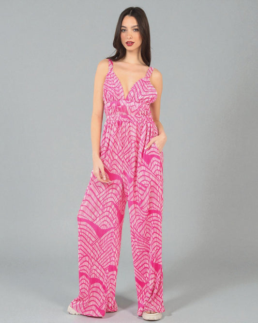 Woman wearing a pink patterned jumpsuit on a gray background
