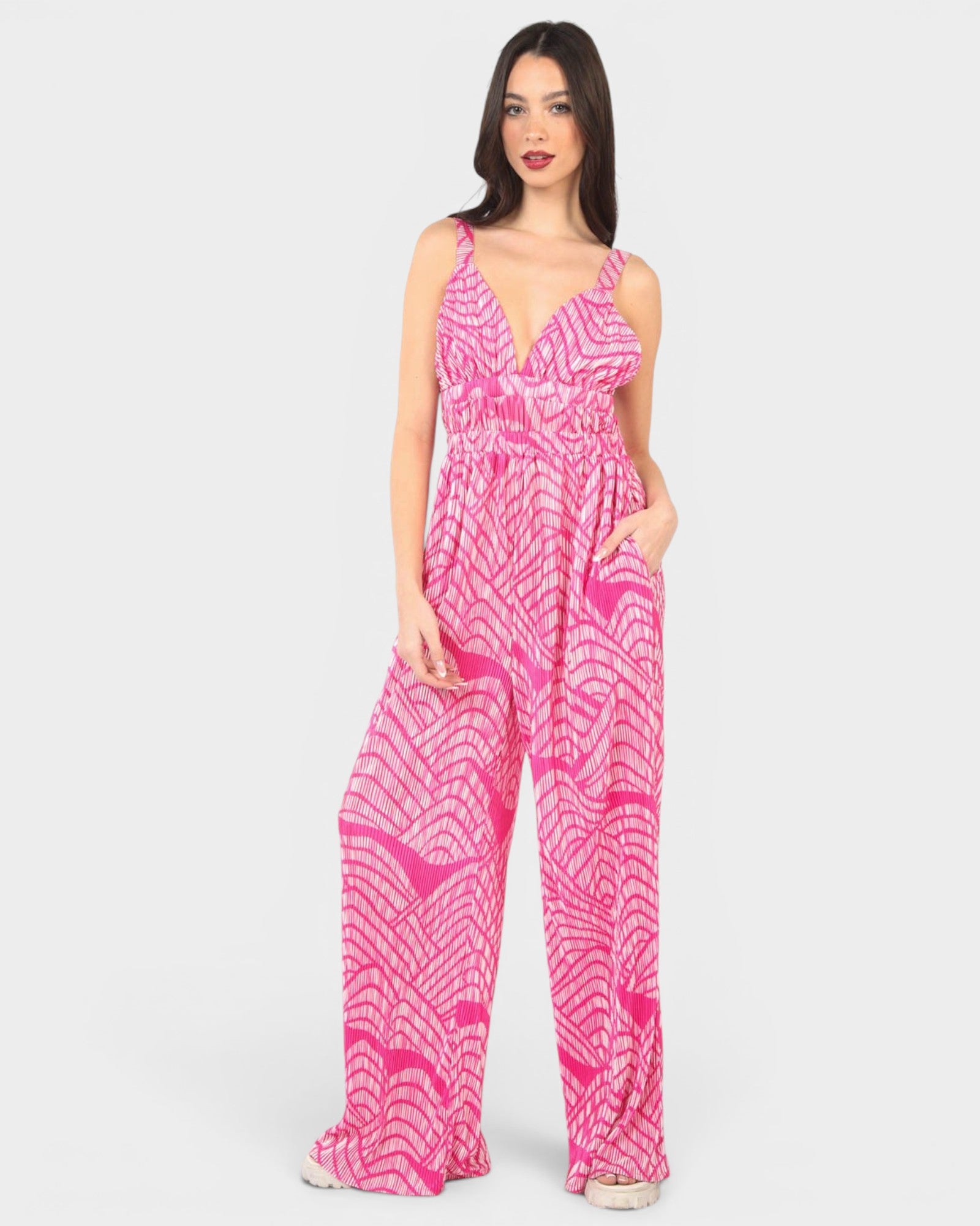 Woman wearing a pink patterned jumpsuit on a white background