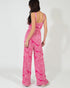 Woman wearing a pink patterned jumpsuit on a white background