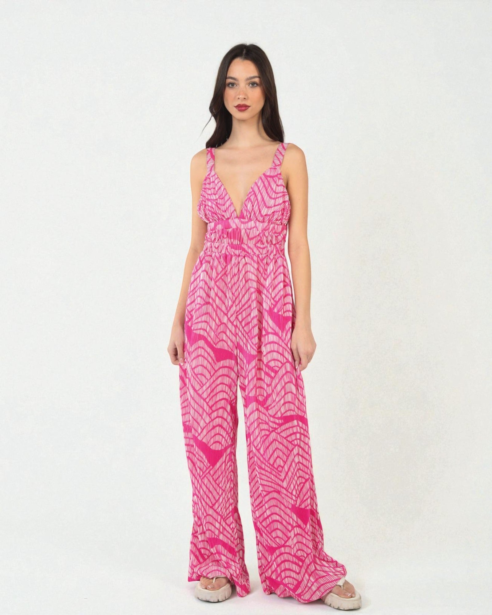 Woman wearing a pink patterned jumpsuit on a white background