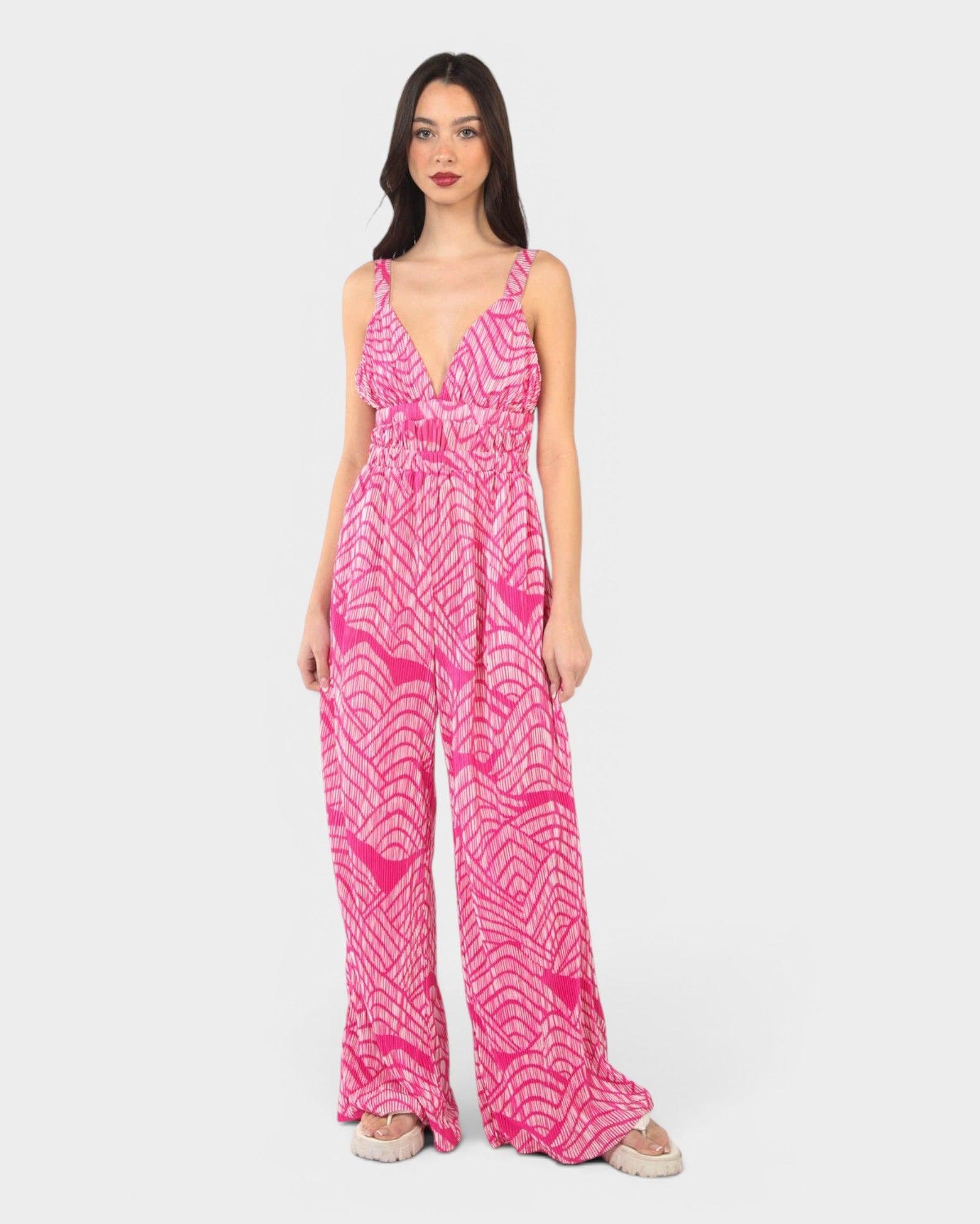 Woman wearing a pink patterned jumpsuit on a white background