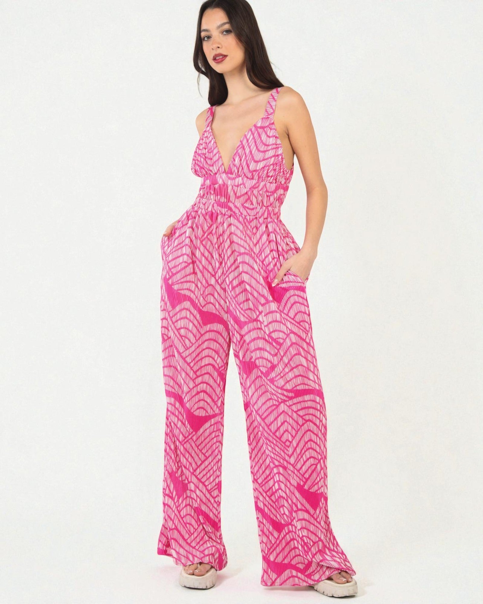 Woman wearing a pink and white patterned jumpsuit on a white background