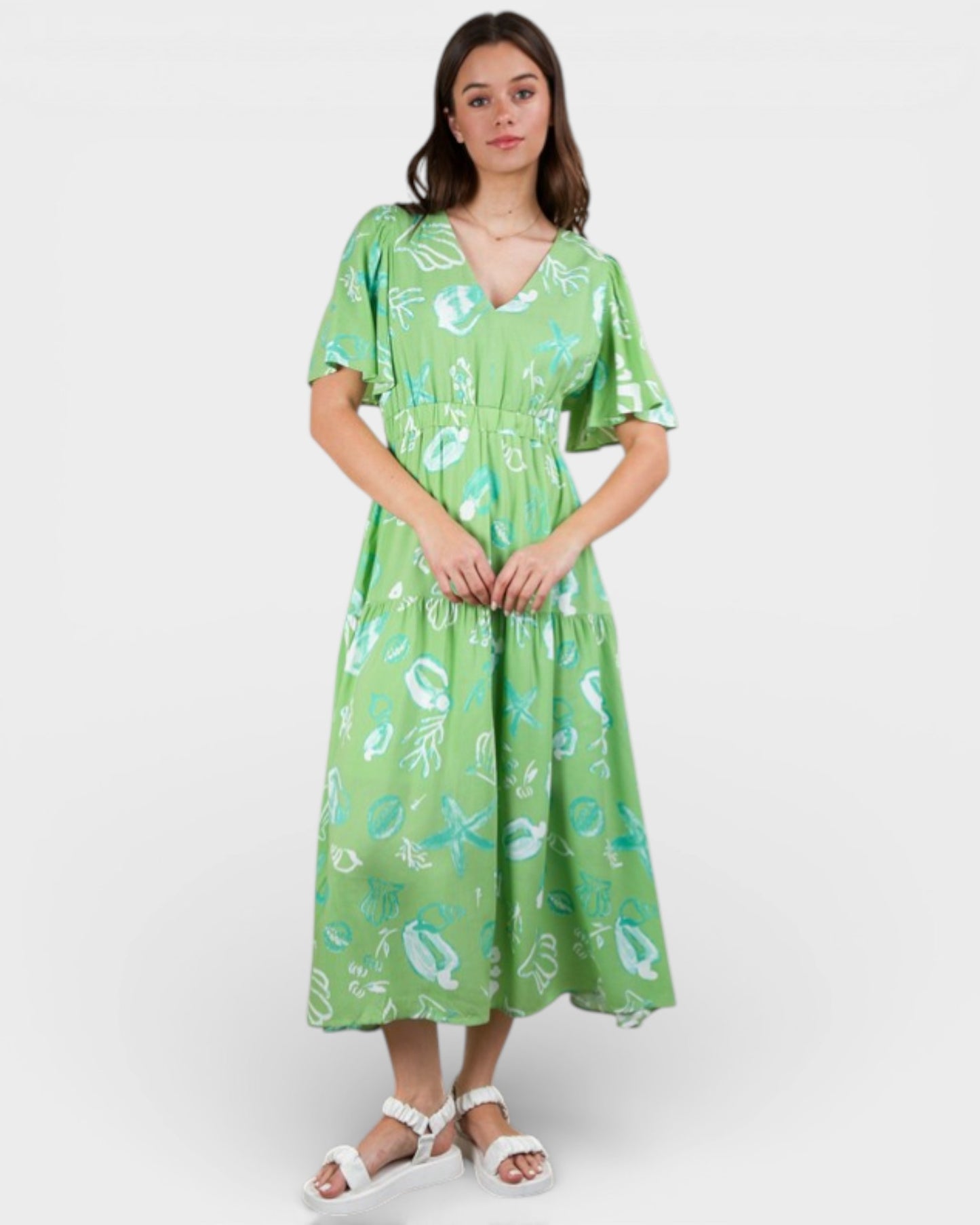 Woman wearing a green dress with a floral pattern on a white background