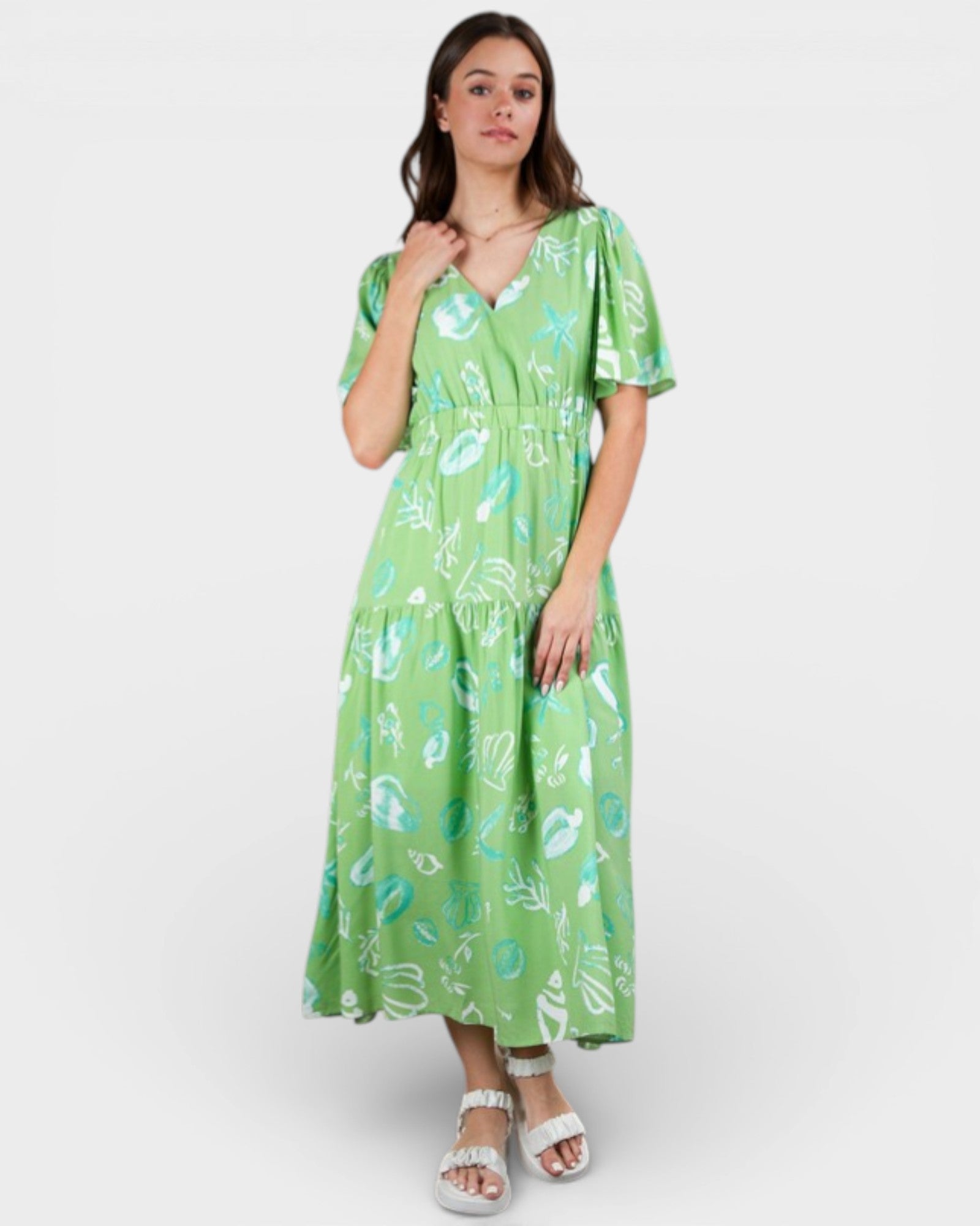 Woman wearing a green dress with a pattern on a white background