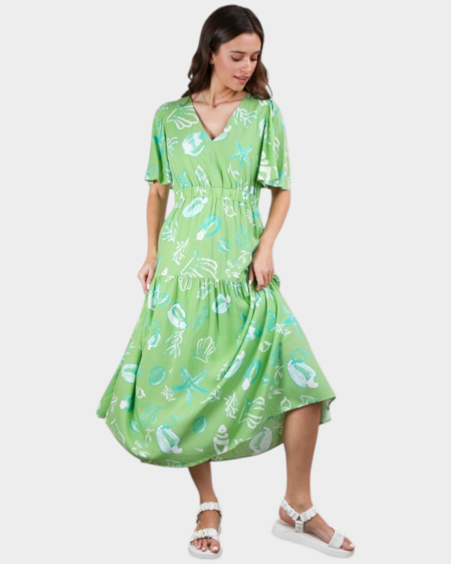 Woman wearing a green dress with a pattern on a white background