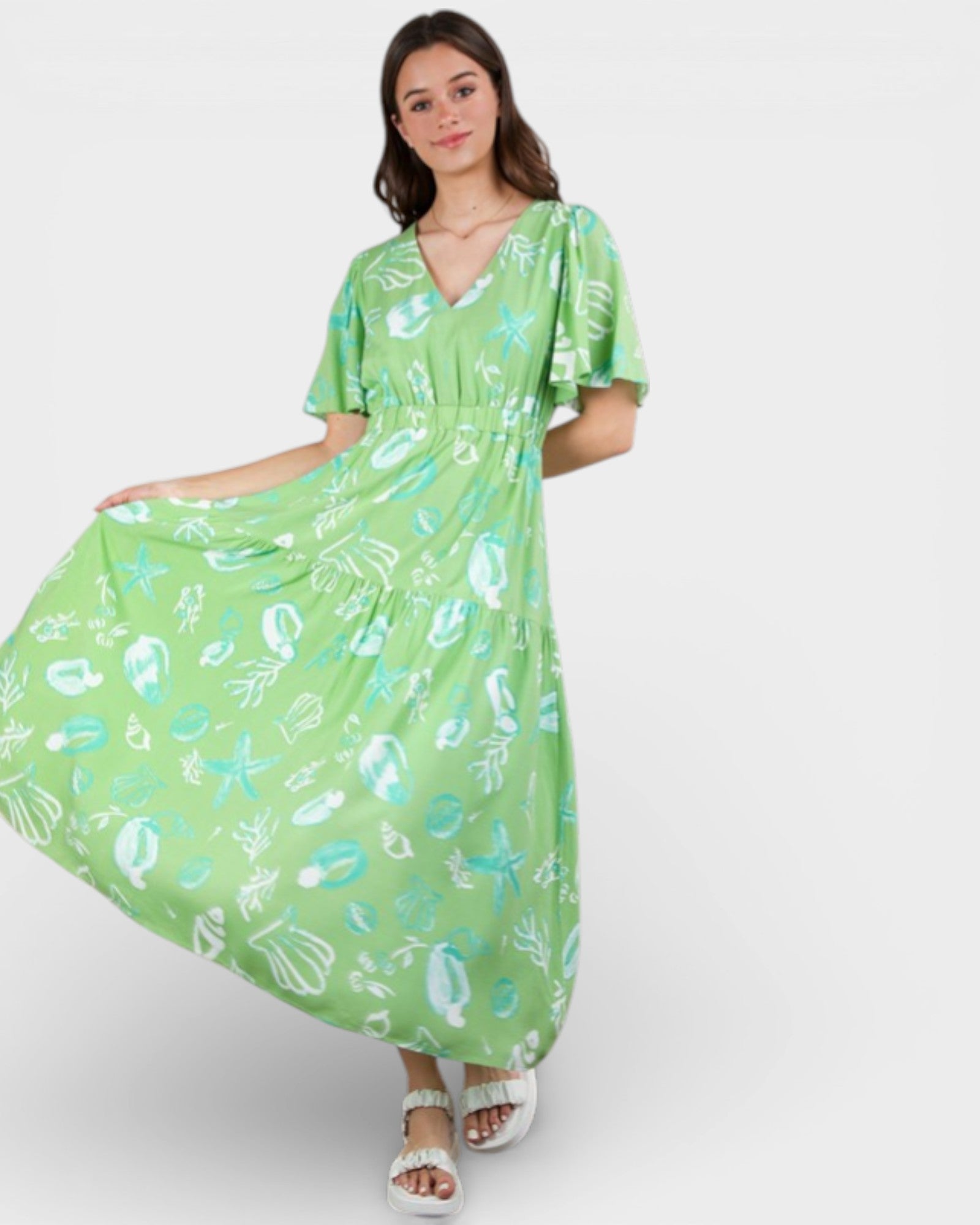 Woman wearing a green dress with a floral pattern on a white background