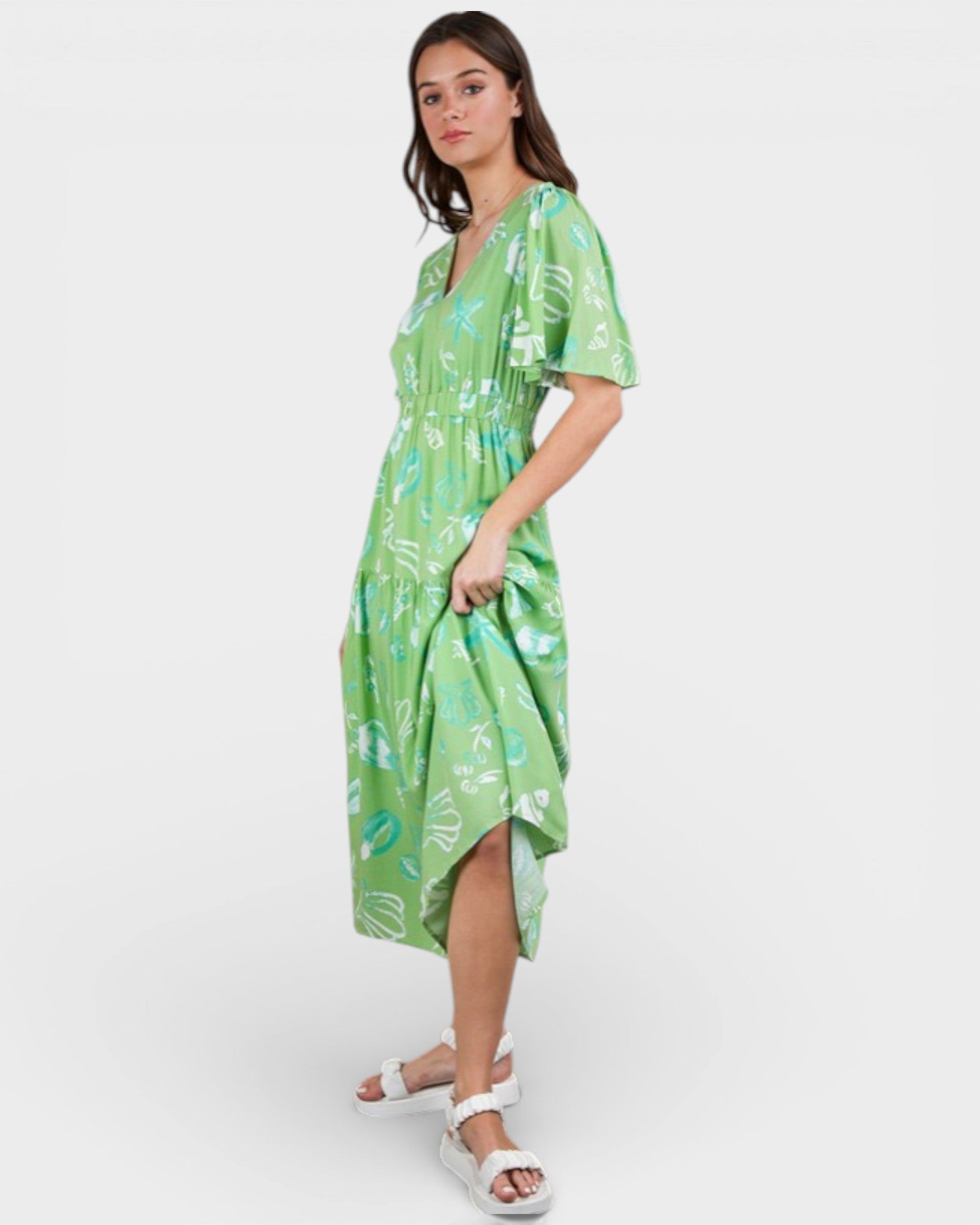 Woman wearing a green patterned dress on a white background