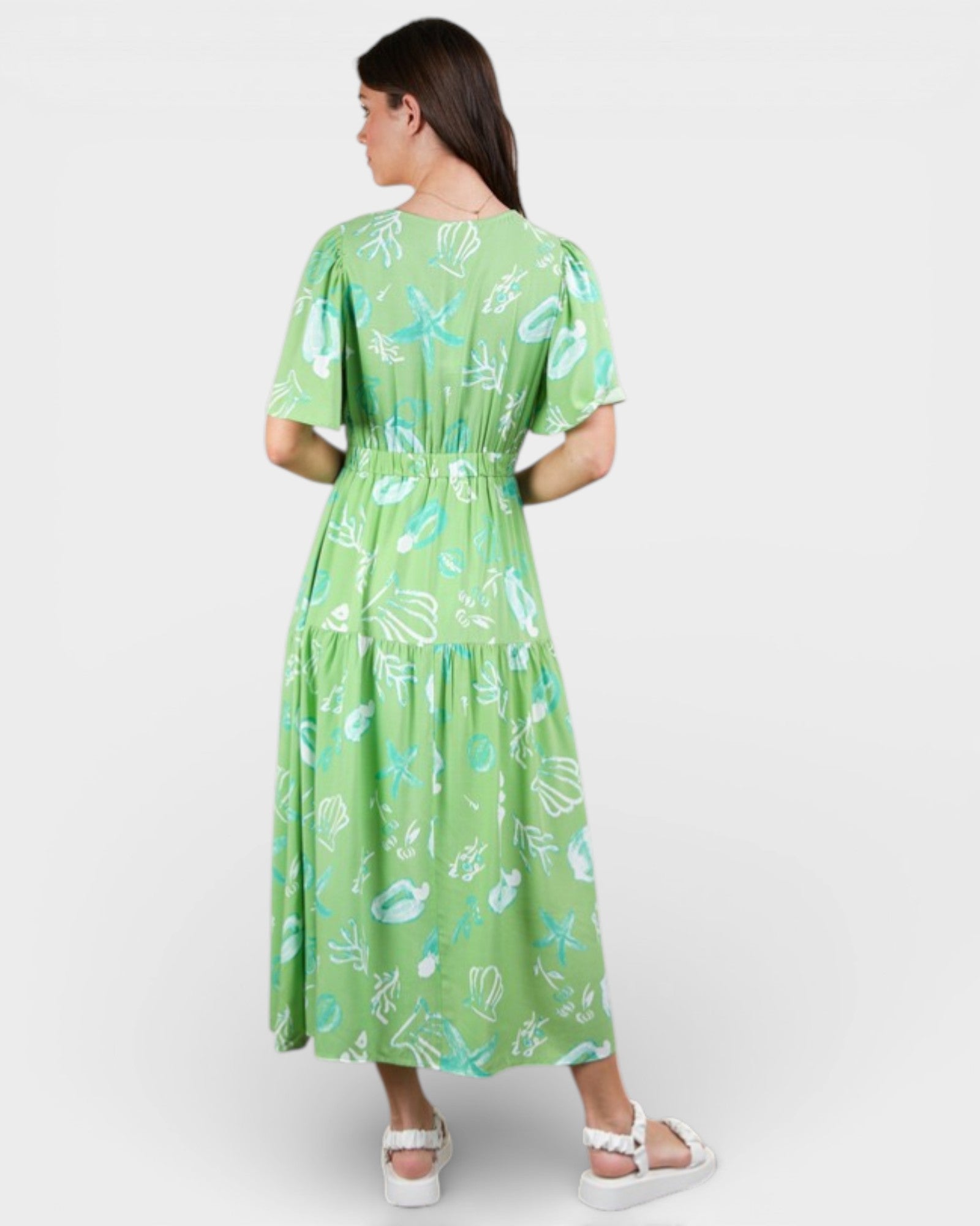 Woman wearing a green dress with a floral pattern on a white background