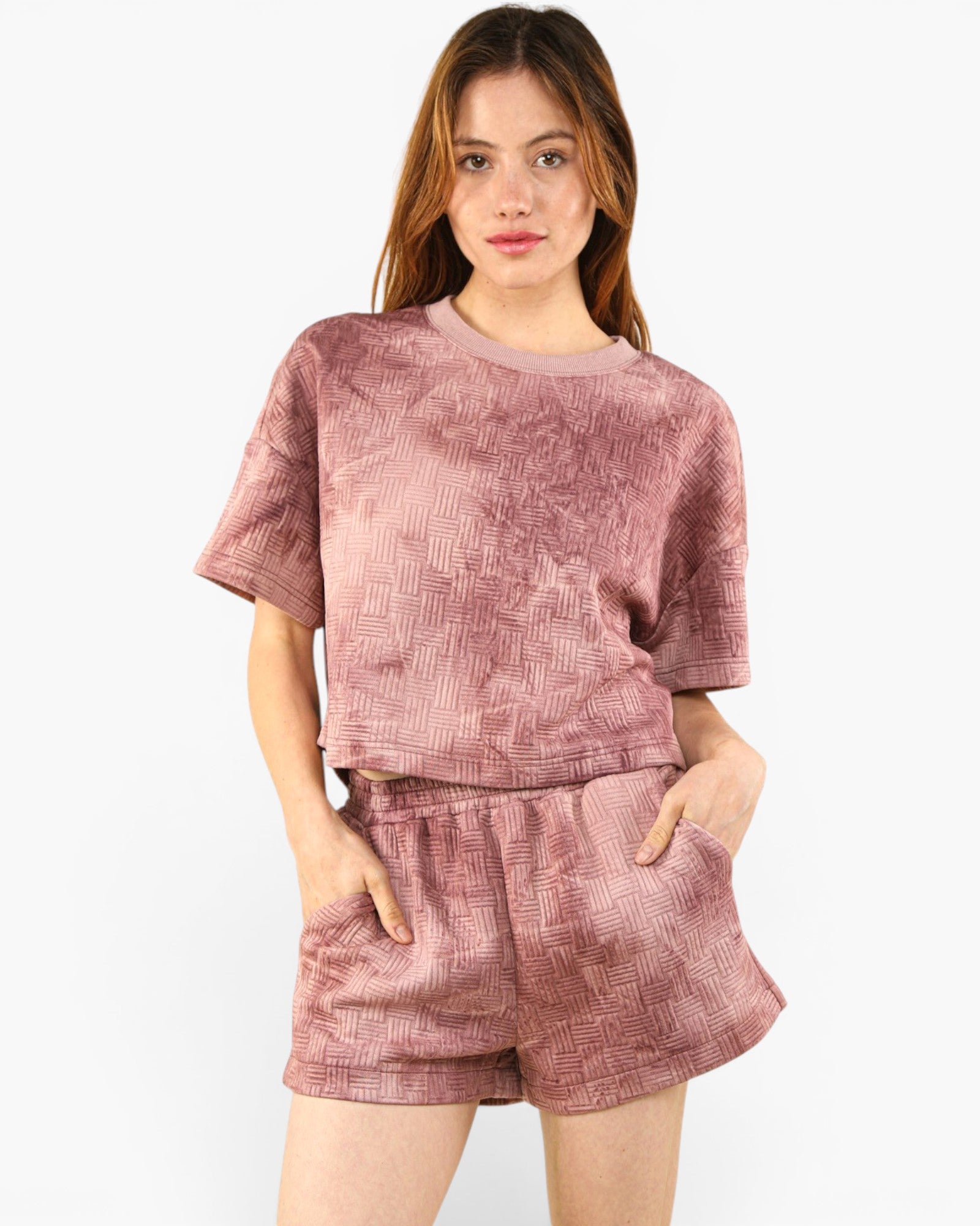 A woman modeling a dusty rose two-piece lounge set featuring a short-sleeve crewneck top and matching shorts with a subtle textured pattern, set against a plain white background.