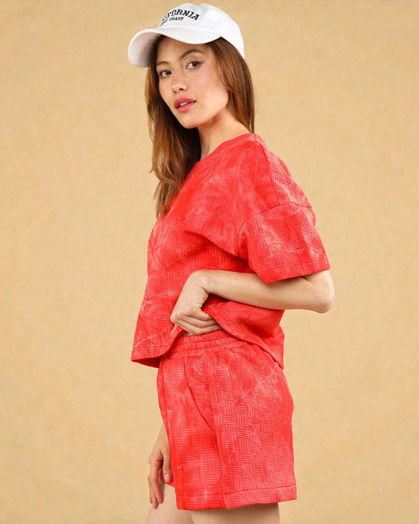 Woman wearing a red outfit and white cap against a beige background