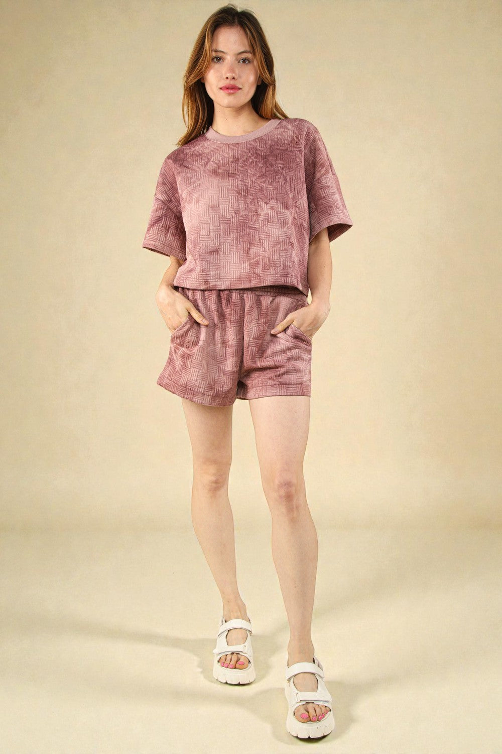 Woman wearing a pink textured outfit on a beige background