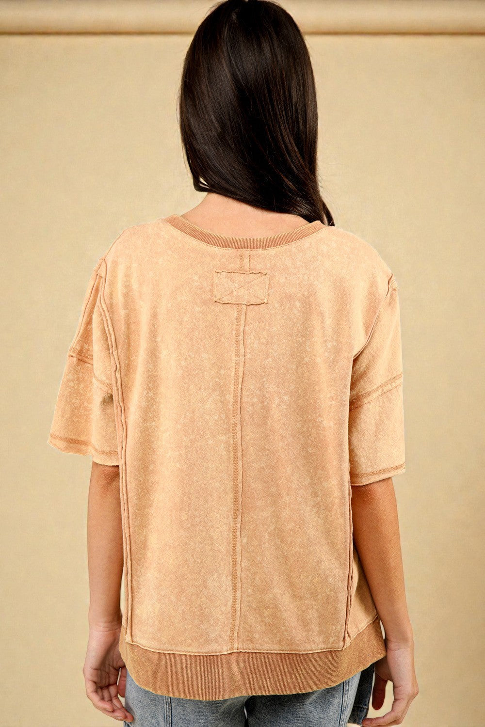 Person wearing a beige top with a plain background