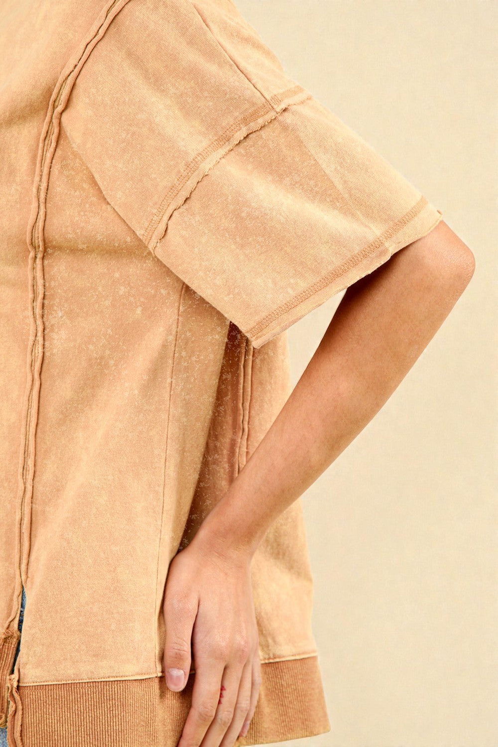 Close-up of a person wearing a beige textured shirt against a beige background