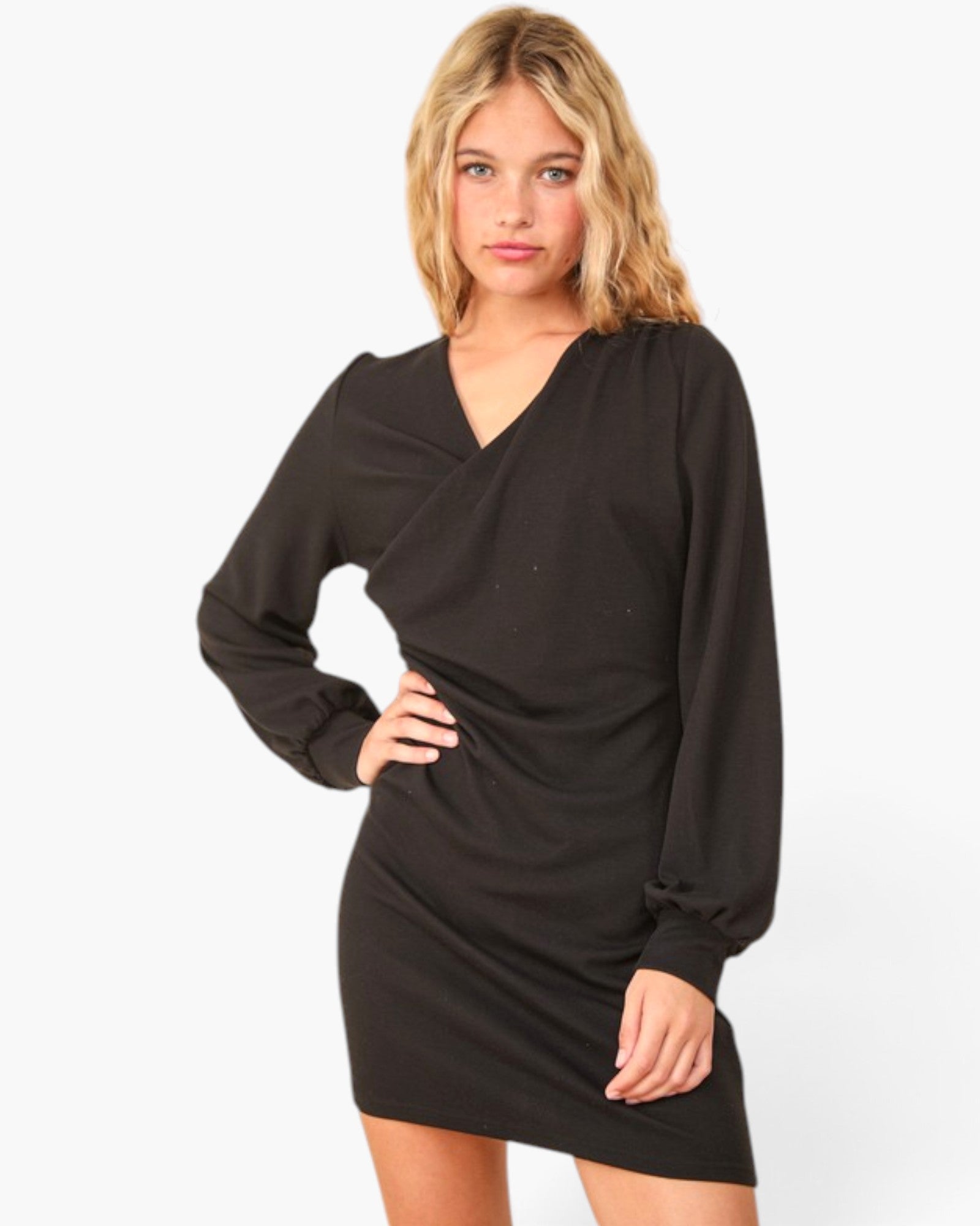 A woman modeling a black long-sleeve wrap-style mini dress against a plain white studio background.