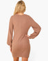 A woman shown from the back wearing a long-sleeve, bodycon mini dress in a muted taupe-brown color, set against a plain light gray studio background.