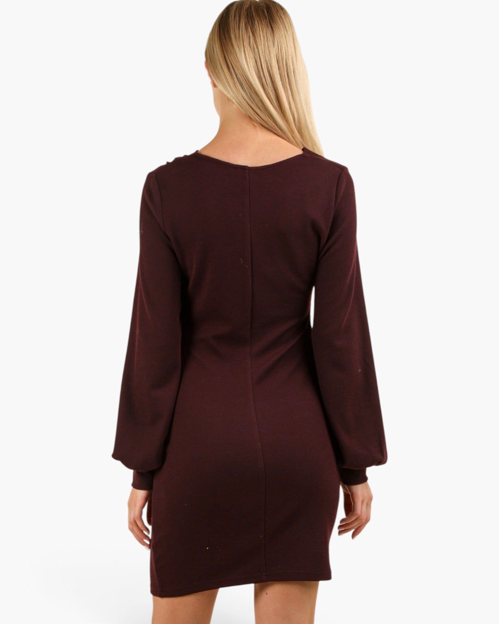 A woman viewed from the back wearing a long-sleeve, bodycon mini dress in a deep burgundy or maroon color, set against a plain white studio background.