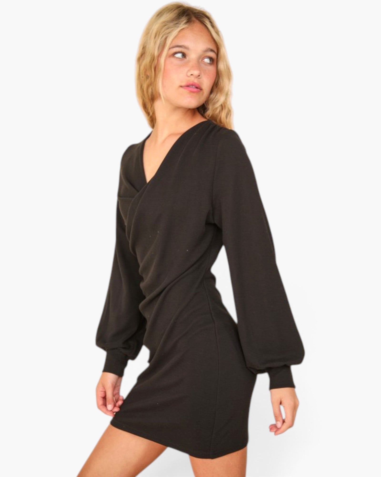 A woman modeling a black long-sleeve mini dress with a wrap-style V-neck and balloon sleeves against a plain white background.