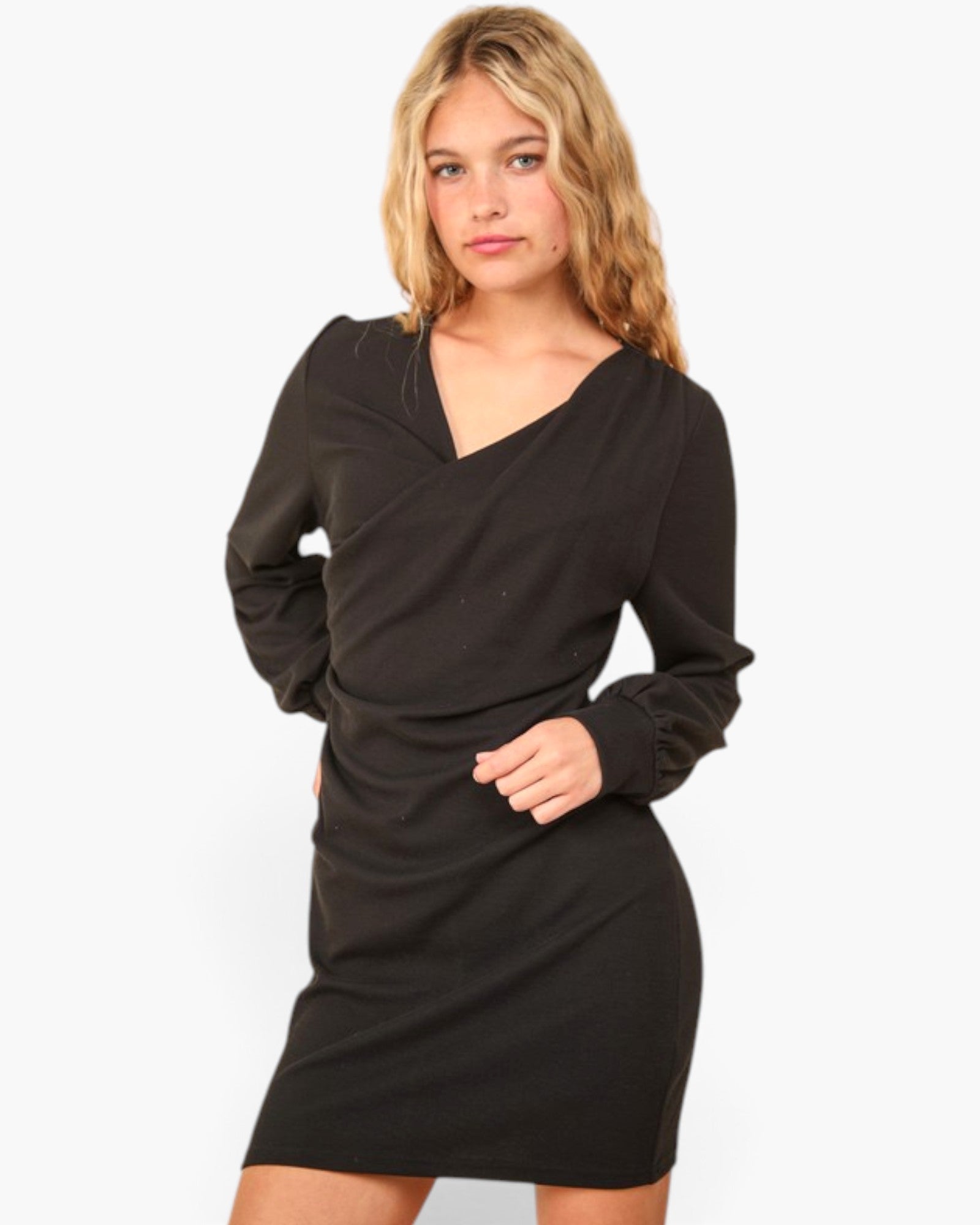 A woman modeling a black long-sleeve wrap-style mini dress against a plain light gray studio background.