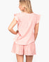 A woman shown from the back wearing a light pink two-piece set with a textured vertical stripe pattern, featuring a short-sleeve top with ruffled edges and matching shorts.