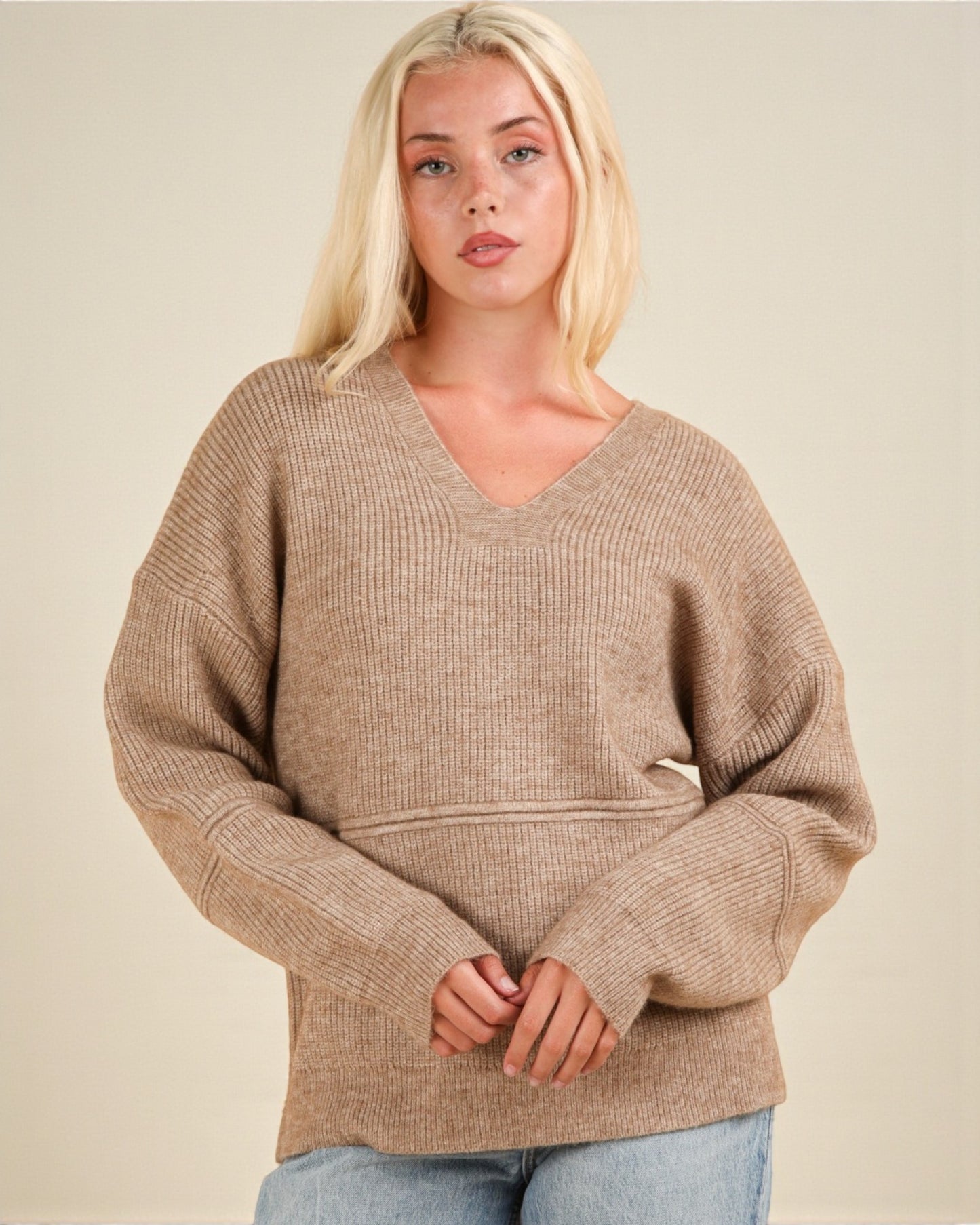 Woman wearing a beige sweater against a plain background