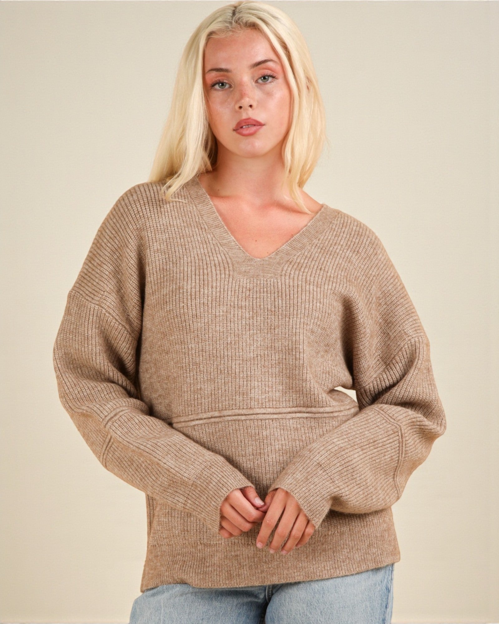 Woman wearing a beige sweater against a plain background