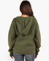 A woman viewed from the back wearing an olive green ribbed knit hoodie with a split hood design, paired with blue jeans, against a plain white background.