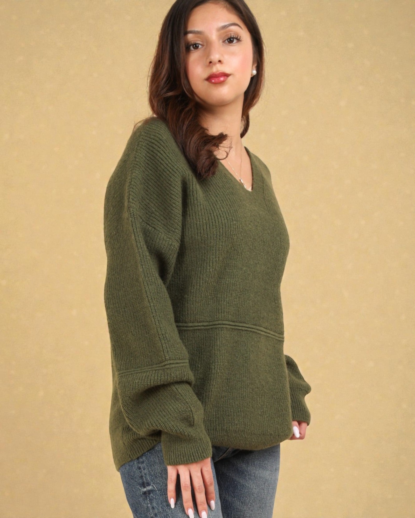 Woman wearing a green sweater against a beige background