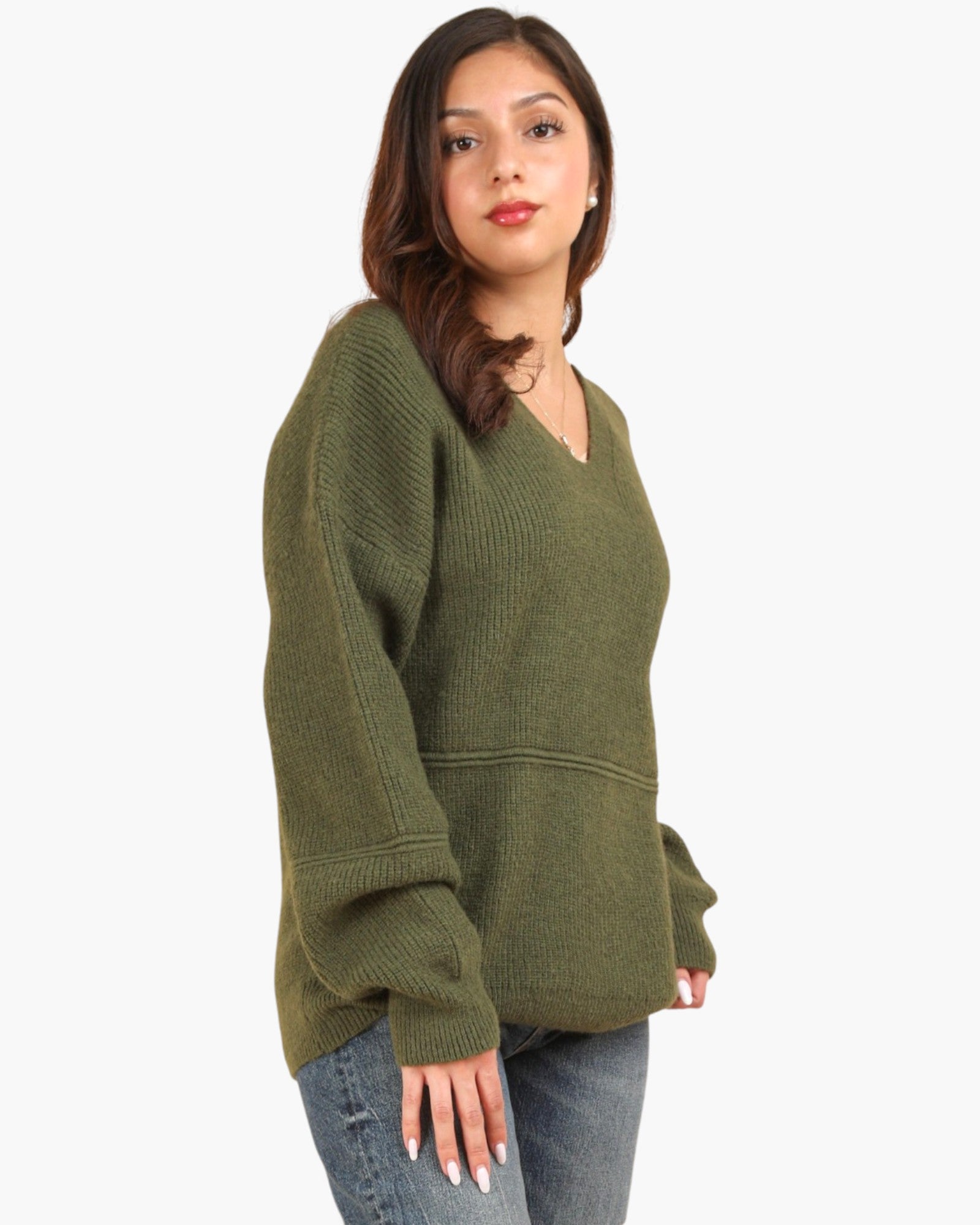 A woman wearing an olive green ribbed knit sweater with a V-neck and long sleeves, paired with blue jeans, photographed against a plain white background.