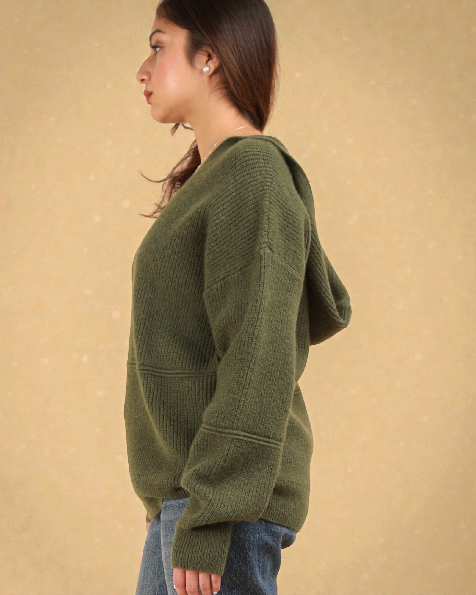 Person wearing a green sweater against a beige background