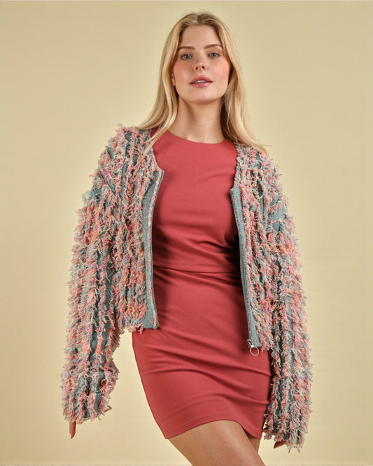 Woman wearing a colorful knit cardigan over a red dress on a beige background