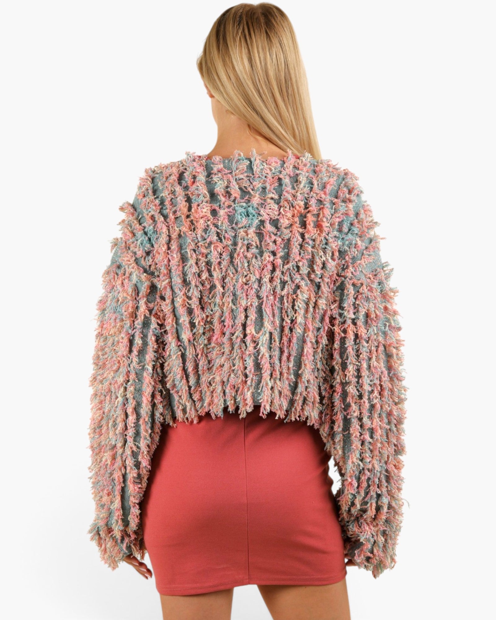 A woman shown from the back wearing a fuzzy, textured long-sleeve sweater in a marled pink, blue, and beige pattern, paired with a coral pink mini skirt, against a plain white background.