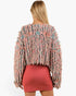 A woman shown from the back wearing a fuzzy, textured long-sleeve sweater in a marled pink, blue, and beige pattern, paired with a coral pink mini skirt, against a plain white background.
