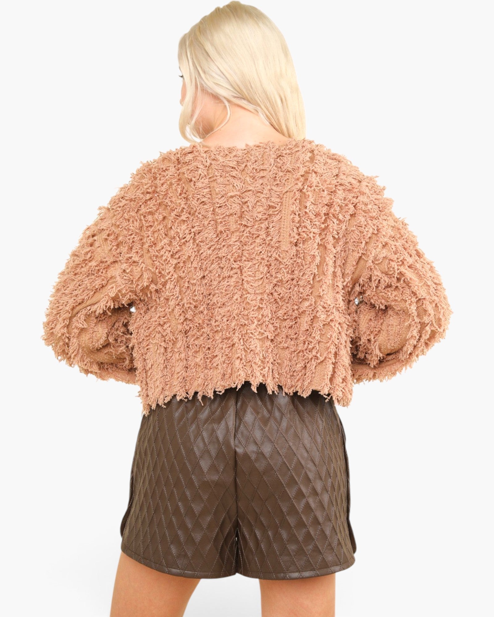 A model shown from the back wearing a textured, fuzzy cropped sweater in a dusty rose color and dark brown quilted faux-leather shorts against a plain white background.