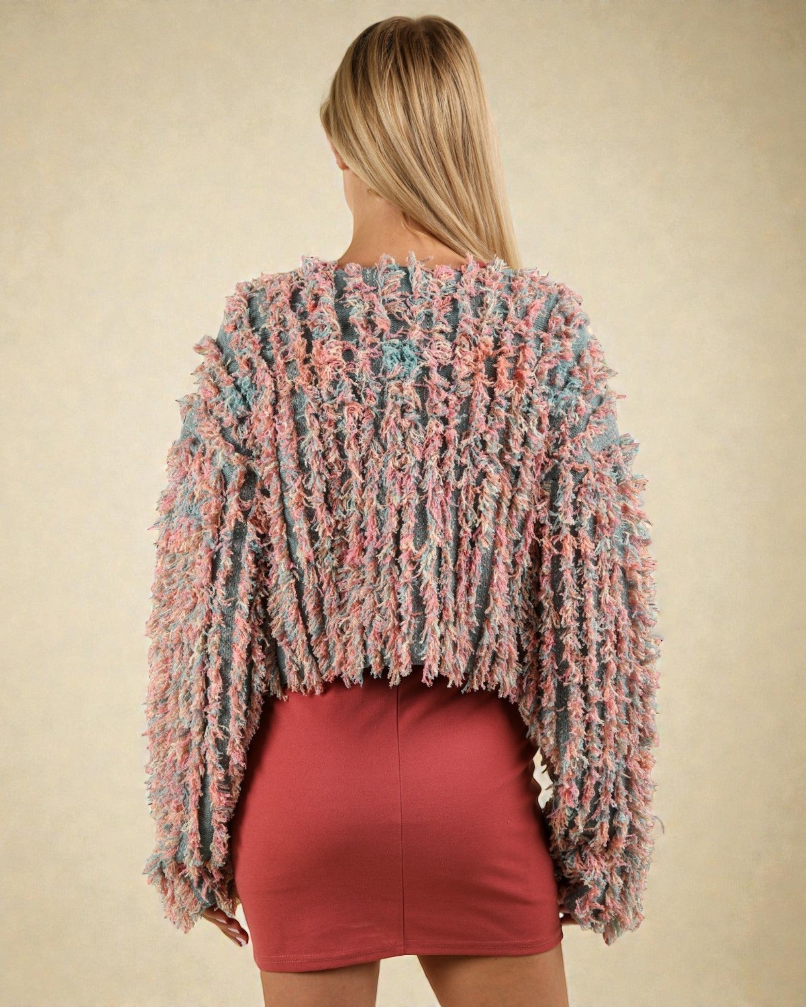 Woman wearing a colorful textured sweater and red skirt on a beige background