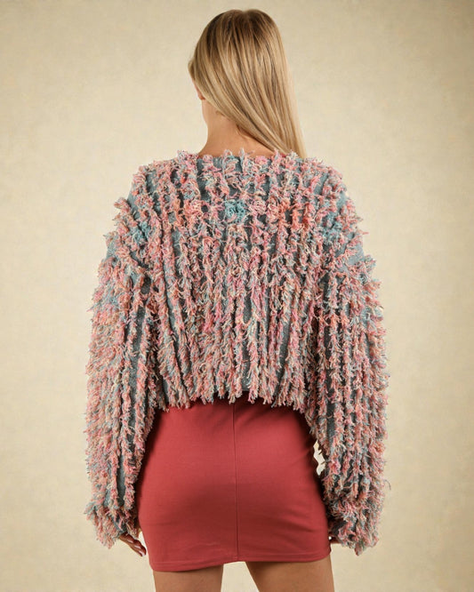 Woman wearing a colorful textured sweater and red skirt on a beige background