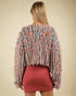 Woman wearing a colorful textured sweater and red skirt on a beige background
