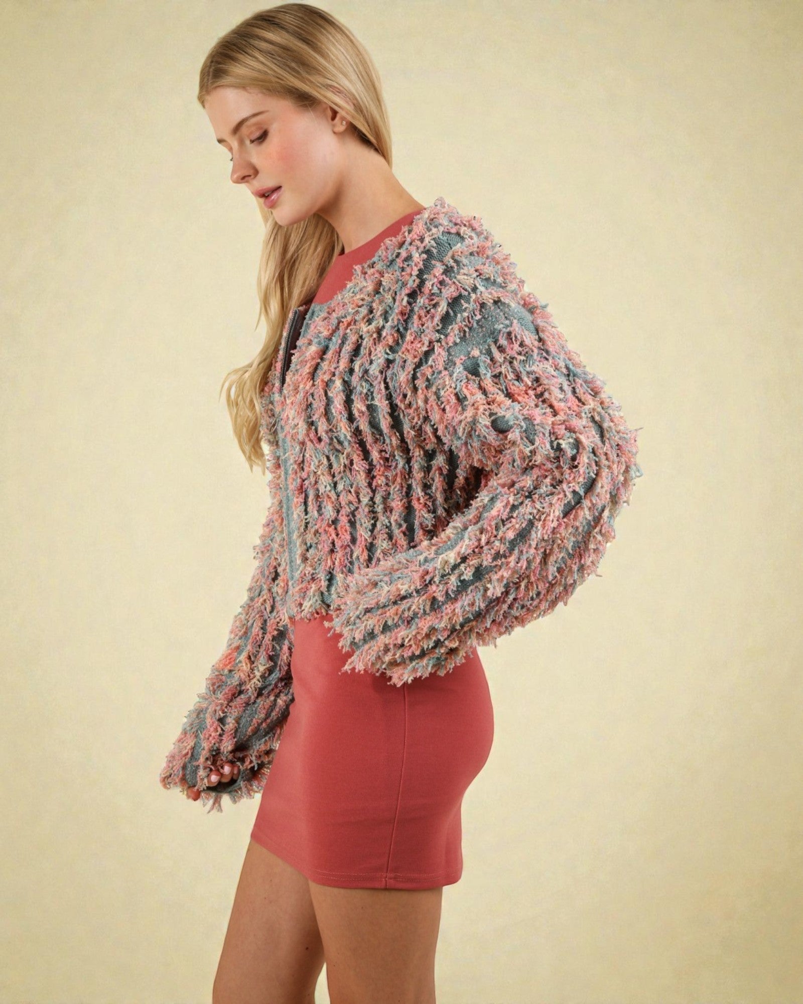 Woman wearing a colorful knitted shawl over a red dress on a beige background
