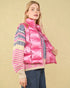 Woman wearing a pink puffer vest over a patterned sweater on a beige background