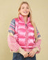 Woman wearing a pink puffer vest with patterned sleeves on a beige background