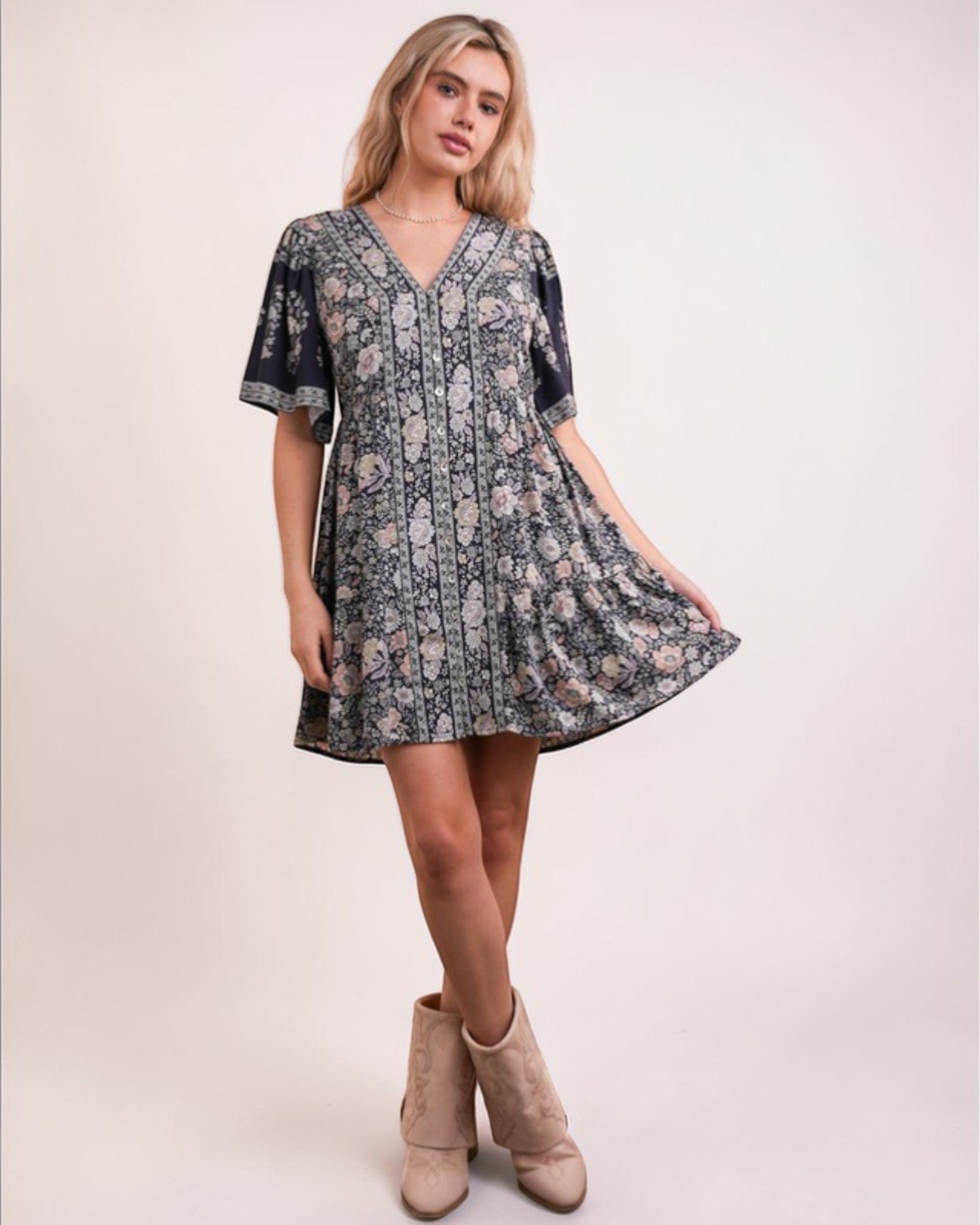 Woman wearing a floral dress with beige boots on a white background