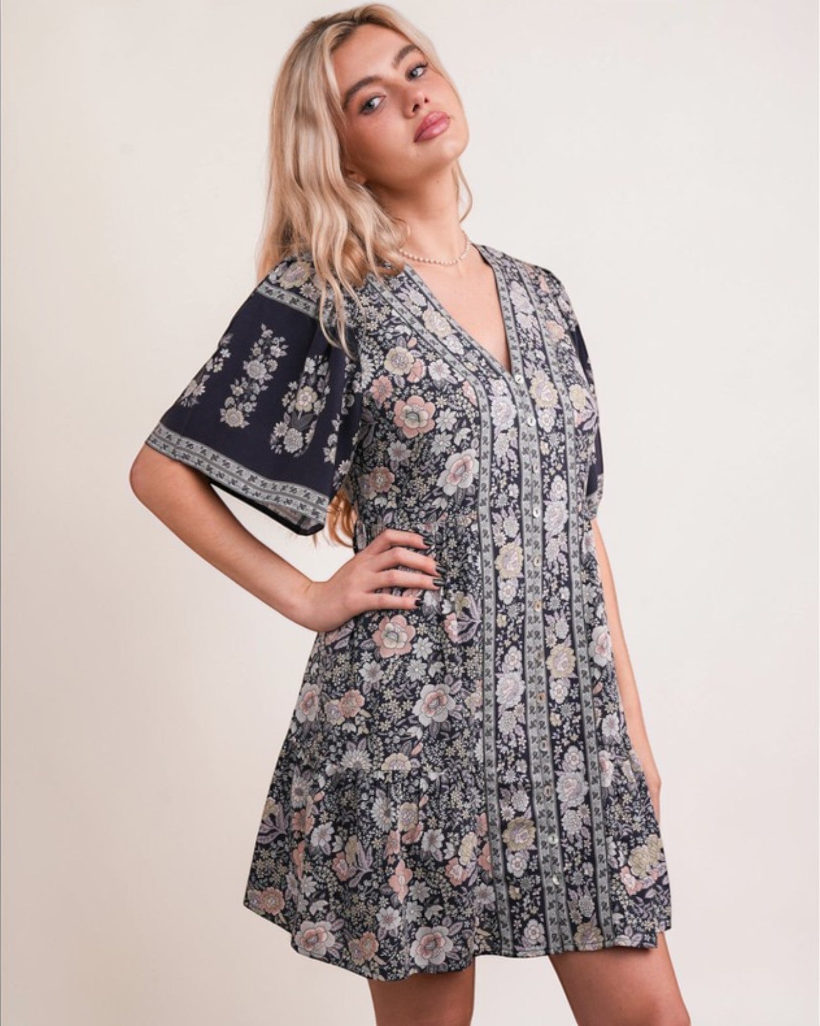 Woman wearing a floral dress with bell sleeves against a plain background