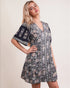 Woman wearing a floral dress with bell sleeves against a plain background