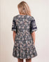 Woman wearing a floral dress with short sleeves on a beige background