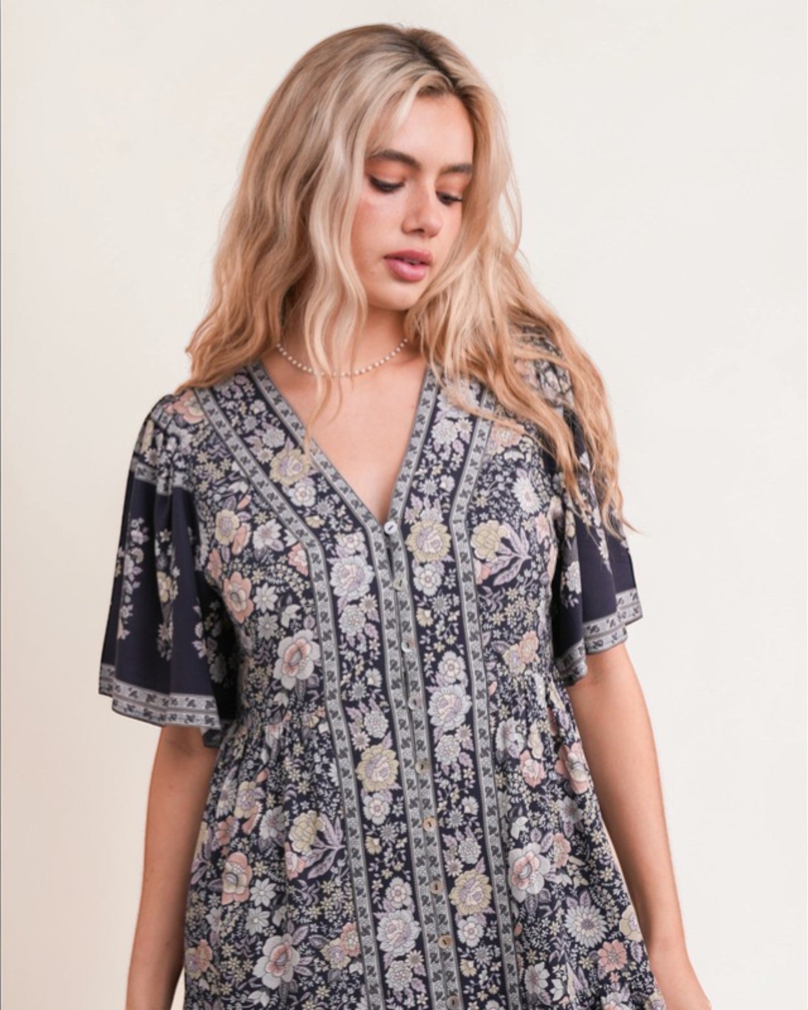 Woman wearing a floral dress against a plain background