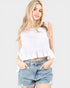 Woman wearing a white sleeveless top and denim shorts on a white background