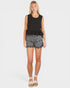 Woman wearing a black sleeveless top and patterned gray shorts on a white background