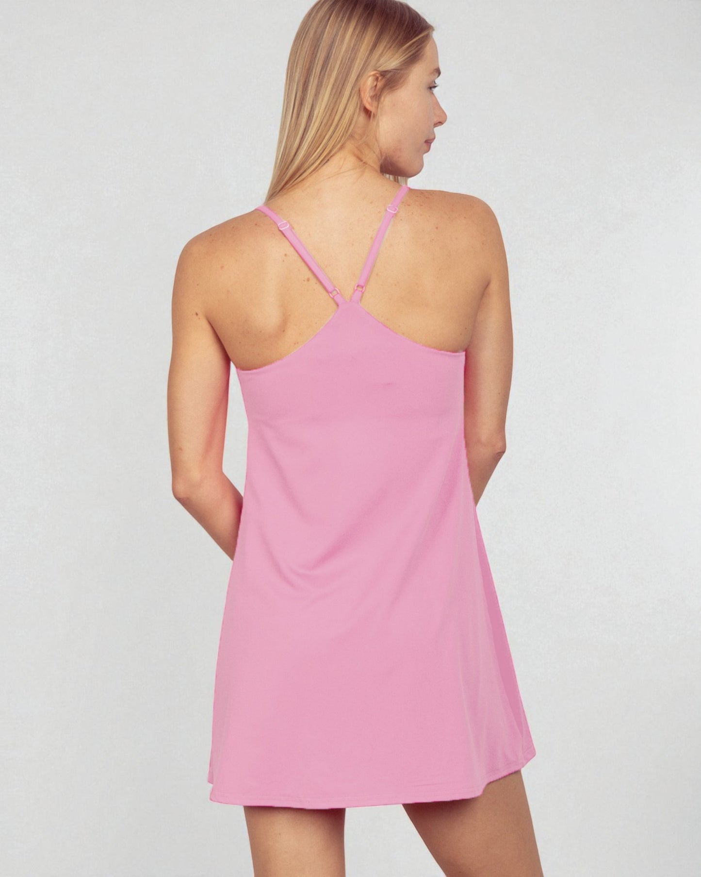 Woman wearing a pink slip dress against a plain background