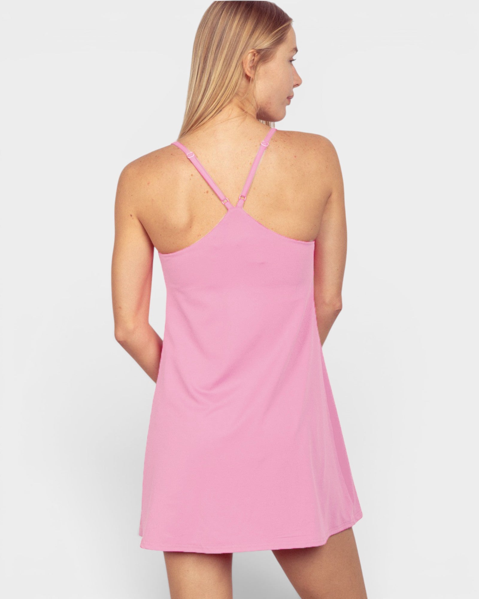 Woman wearing a pink slip dress against a white background